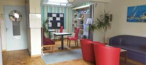 a waiting room with a table and red chairs at Hotel La Chaumière in Saint-Jean-de-Monts