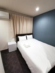 a bedroom with a large white bed and a blue wall at GLOU Higashi Shinjuku in Tokyo