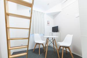 um quarto com duas cadeiras, uma mesa e uma televisão em GLOU Higashi Shinjuku em Tóquio