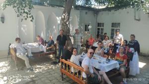 a group of people sitting at tables in a yard at Minorai Xurd in Bukhara