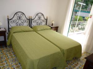 a bedroom with a bed with green sheets and a window at Casa Fortunata in Positano