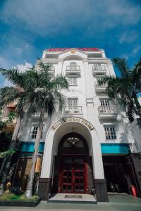 a white building with palm trees in front of it at Sunflowers Hotel Airport in Ho Chi Minh City