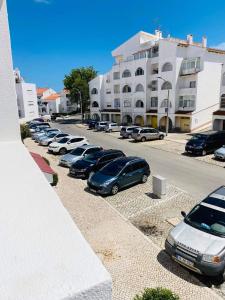 een rij auto's geparkeerd op een parkeerplaats naast een gebouw bij Albufeira Beach side Apartment in Albufeira