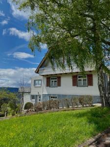 a white house on a hill with a tree at Ferienhaus mit 5* Luxus im Schwarzwald in Gemeinde Aichhalden