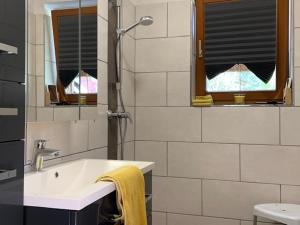 ein weißes Bad mit einem Waschbecken und einer Dusche in der Unterkunft Haus Schmidl in Kötschach