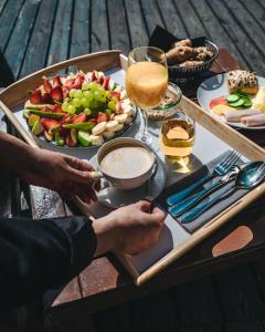 a person holding a tray of food on top of a wooden table at First Hotel Millennium in Oslo