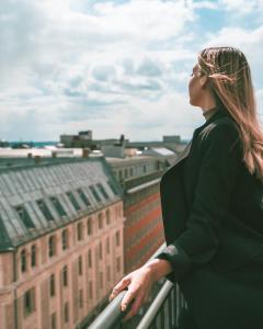 Eine Frau steht auf einem Balkon mit Blick auf eine Stadt in der Unterkunft First Hotel Millennium in Oslo