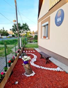 a bench sitting next to a building with flowers at Hócza House Poroszló in Poroszló