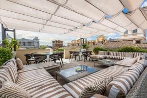 un patio esterno con divani, tavoli e sedie di Amazing Penthouse Piazza Venezia a Roma
