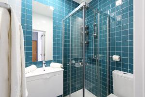 a blue tiled bathroom with a toilet and a shower at Big Wave Apartment in Nazaré