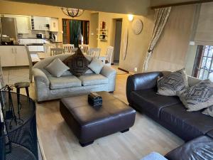 a living room with two leather couches and a kitchen at Miramichi Guest House in Dullstroom +16 photos