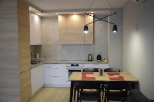 uma cozinha com uma mesa de madeira e cadeiras num quarto em Apartament Pod Papugami em Toruń