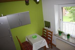 ヘルマンスブルクにあるFerienwohnungen Manfred Peters Bavenの緑の壁のキッチン(小さなテーブルと椅子付)
