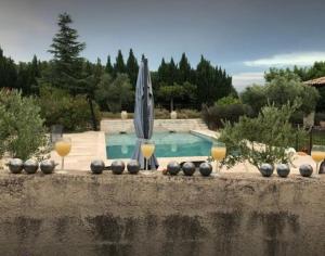 una piscina con dos copas de vino y una sombrilla en Bastide CAMPAGNE CANAL, en Cucuron