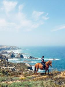 a person riding a horse on a hill overlooking the ocean at Monte Da Moita Nova in Cavaleiro