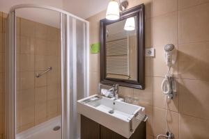 a bathroom with a sink and a mirror and a shower at Tündérkert Hotel Noszvaj in Noszvaj