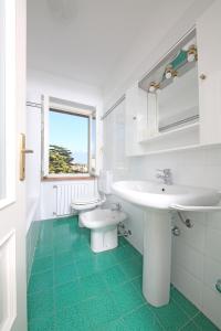 bagno bianco con lavandino e servizi igienici di Apartment Casa Caterina a Gargnano