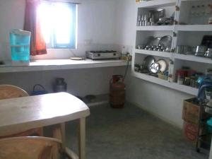 カジュラーホーにあるVamoose Babluのキッチン(テーブル付)、窓、カウンターが備わります。