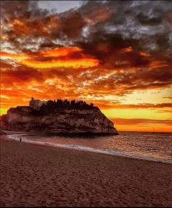 - un coucher de soleil sur une plage avec un château sur un rocher dans l'établissement Afrodite Accomodation, à Tropea