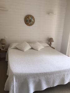 cama blanca con almohadas y reloj en la pared en Villa Argi Eder, en San Juan de Luz