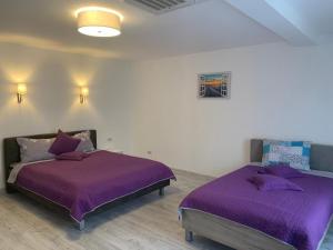 two beds in a room with purple sheets at Ansamblul rezidential Phoenix in Orăştie