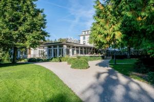 ein großes weißes Gebäude mit Rasen und Bäumen in der Unterkunft Park Hotel Winterthur in Winterthur