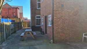 a wooden bench sitting next to a brick wall at K Stunning 5 Bed Sleeps 8 Families Workers by Your Night Inn Group in Wolverhampton