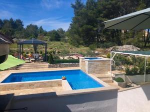 a swimming pool in a backyard with an umbrella at Holiday Home Ela in Dračevica