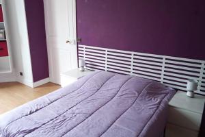 une chambre avec un lit avec un mur violet dans l'établissement Apt T2 41m2 WIFI 2* 4-6 pers. La BOURBOULE, à La Bourboule