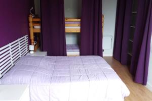 - une chambre avec un grand lit et des rideaux violets dans l'établissement Apt T2 41m2 WIFI 2* 4-6 pers. La BOURBOULE, à La Bourboule