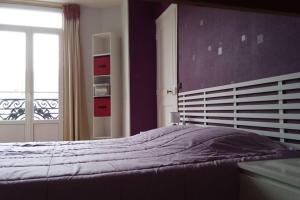 une chambre avec un lit aux murs violets et une fenêtre dans l'établissement Apt T2 41m2 WIFI 2* 4-6 pers. La BOURBOULE, à La Bourboule
