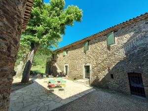 un edificio in pietra con tavoli e sedie in un cortile di Les Jardins de Falguière a Saint-Jean-du-Gard