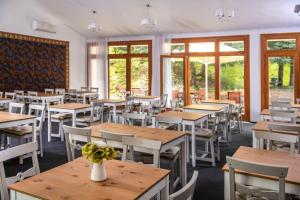 ノスヴァイにあるTündérkert Hotel Noszvajのテーブルと椅子と窓のあるダイニングルーム