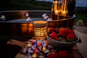 un tazón de fresas en una mesa junto a una bañera de hidromasaje en Orchard Valley Glamping, en Otorohanga