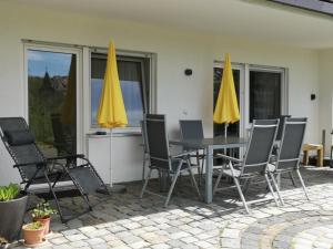 a patio with a table and chairs and yellow umbrellas at Appartment Schlossblick in Wiesenthau