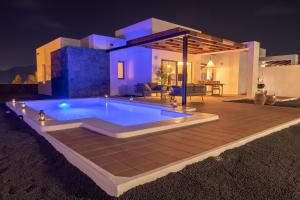 a swimming pool in front of a house at night at Villalia Famara in Playa Blanca