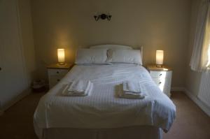 una camera da letto con un grande letto bianco con due luci di Minehead mews cottage a Minehead