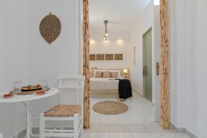 a white bedroom with a bed and a table and a table at Naxian Horizon in Naxos Chora