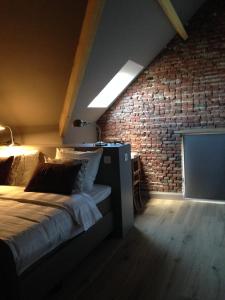 1 dormitorio con cama y pared de ladrillo en B&B Droomzoet, en Herentals