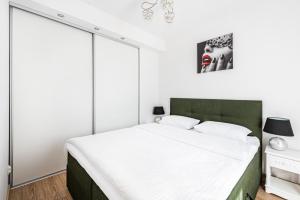 a bedroom with a large white bed with a green headboard at Apartament Zielony OPTILOCUS in Gdańsk