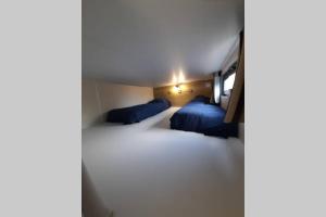 2 Betten in einem kleinen Zimmer mit blauen Kissen in der Unterkunft Maison Tiny House 2 chambres Soulac a 500m plage in Soulac-sur-Mer