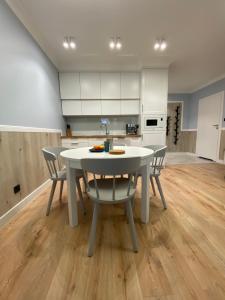 a kitchen with a white table and chairs in a room at APARTAMENT MORSKI KRYNICA MORSKA in Krynica Morska