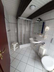 a white bathroom with a sink and a toilet at Hotel & Restaurant Aragwi in Salzwedel