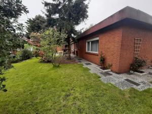 a red brick house with a grass yard at Fewo Rose in Norden