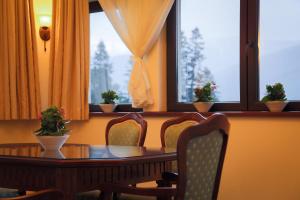 una sala da pranzo con tavolo, sedie e finestre di Hotel Foisorul cu Flori a Sinaia