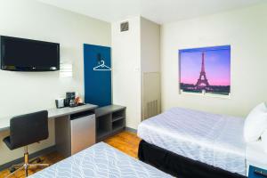 a hotel room with a bed and a desk with a television at Studio Z, Ascend Hotel Collection in Saint Robert