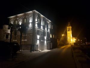 ein beleuchtetes Gebäude mit einem Uhrturm in der Nacht in der Unterkunft Vila Djuro Mikijelj in Donji Stoliv