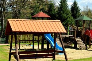 a playground with an orange roof and a slide at Domki Olina in Polańczyk