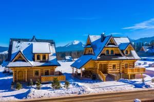 una casa en la nieve con montañas en el fondo en GÓRSKIE DOMKI Murzasichle, en Murzasichle