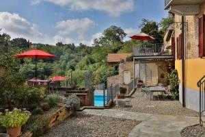 una casa con piscina e patio con ombrelloni di Villa Pesce, Mombaruzzo a Mombaruzzo